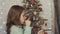 Little girl decorating wooden Christmas tree with toys