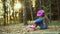 A little girl in a denim suit fastens roller skates. Sitting on the ground on an autumn day