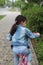 Little girl in a denim suit rides a pink bike along a brick multi-colored path in a spring city