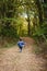 A little girl in a denim suit runs along a forest path.