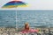 Little girl with diving mask under sunshade on beach