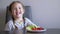 The little girl does not want to eat vegetables. Child gets angry and pushes the plate aside