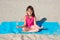 Little girl does yoga on the beach. The concept of sport and active play in the summer. Beach gymnastics