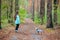 Little girl with dog walking on the road in forest