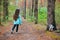 Little girl with dog walking on the road in forest