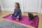 Little girl doing the yoga crossed-legged sitting pose with grey cat