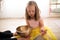 Little girl with down syndrom sitting on the floor in ballet dancing studio and making sound on tibetian singing bowl.
