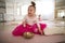 Little girl with down syndrom sitting on the floor in ballet dancing studio and making sound on tibetian singing bowl.