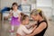 Little girl with down syndrome cuddling with her mother during ballet class. Concept of integration disabled children