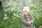 Little girl with Down syndrome in the mouth pulls dandelions