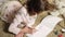 Little girl drawing colorful flowers in her album, dreaming of summer and warmth