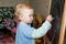 Little girl draws with chalk on a blackboard