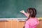 Little girl draws with chalk on a blackboard. The child performs a learning task. Babe starts school in first grade. School