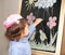 The little girl draws color pieces of chalk on an easel