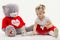 Little girl draws on the floor. Near a large soft toy. White background