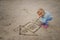 Little girl draws in the sand