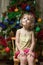 Little girl dreamily looking up on chair near Christmas tree