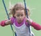Little girl dreamily swings in a swing