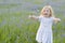 A little girl in a dress and with a bouquet of flowers laughs and plays in a field with cornflowers on a summer day