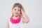 A little girl in a dress with butterflies corrects blond hair