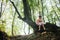 Little girl in a dress with doll sits on a tree in the forest