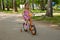 Little girl in a dress rides a four-wheeled bike on a summer alley