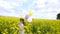 Little girl in a dress running through yellow wheat field with balloons in hand