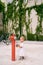Little girl in a dress stands near a red fire hydrant in front of the building