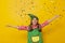 Little girl dressed as Christmas elf throwing colorful confetti