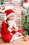 Little girl dressed costume Santa Claus by fireplace. Christmas