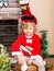 Little girl dressed costume Santa Claus by fireplace. Christmas