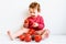 Little girl dressed in red squeezes tomatoes and makes a mess by savoring them