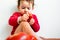 Little girl dressed in red squeezes tomatoes and makes a mess by savoring them