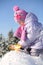 Little girl dressed in warm clothes digs with shovel and sits