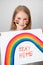 Little girl drew rainbow and poster stay home.