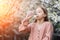 A little girl drinks clean fresh water from a plastic bottle near a flowering tree in the garden