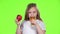 Little girl drinks juice from a glass and holds an apple. Green screen. Slow motion