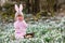 Little girl with Easter bunny ears making egg hunt in spring forest on sunny day, outdoors. Cute happy child with lots