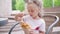 Little girl eat bubble waffle with ice cream sitting outdoor cafe summer day