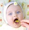 little girl eating first solid meal pumpkin puree with mouth wide open