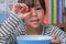 Little girl eating fresh red grapes at home in the living room. Cute young Asian girl eats healthy fruits and milk for her meal.