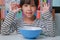 Little girl eating fresh red grapes at home in the living room. Cute young Asian girl eats healthy fruits and milk for her meal.