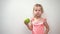 Little girl eating green fresh sour apple at white background