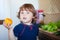 Little girl eating tomato in the kitchen