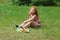 Little girl eats apple on lawn in green summer par