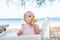 A little girl eats a delicious banana on a tropical sandy beach. The baby meets with food. The development of fine motor skills.