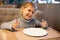 Little girl with empty plate in restaurant