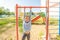 A little girl is engaged on a horizontal bar in the yard