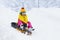 Little girl enjoying a sleigh ride. Child sledding. Toddler kid riding a sledge. Children play outdoors in snow. Kids sled in the