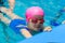 A little girl of European appearance in glasses in the pool, shows the language and looking at the camera